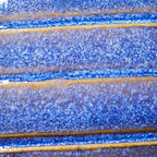 Nahaufnahme einer strukturierten blauen und gelben Glasur mit horizontalen Rillen - eine ideale Inspiration für Keramiker oder alle, die an der Masterclass teilnehmen: Glasuren entschlüsselt, um ihre eigenen einzigartigen Keramikoberflächen zu entwickeln.
