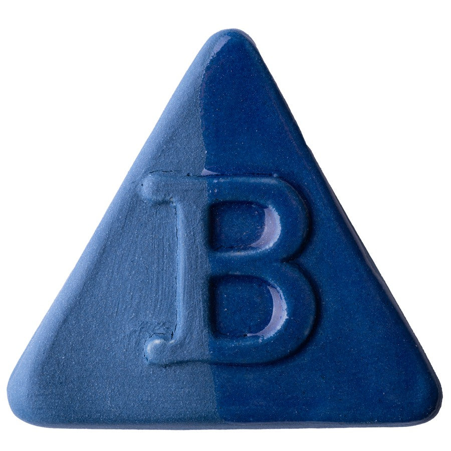 Die Botz Edition ist ein dunkelblaues, dreieckiges Stück mit einem erhabenen „B“ in der Mitte und einem subtilen Farbverlauf, gefertigt aus Steinzeug-Engoben und mit transparenter Glasur für mehr Tiefe veredelt.