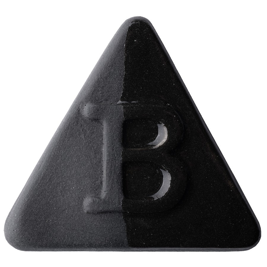Die Botz Edition ist ein schwarzes, dreieckiges Objekt mit einem erhabenen Buchstaben B in der Mitte und einer transparenten Glasuroberfläche auf weißem Hintergrund.