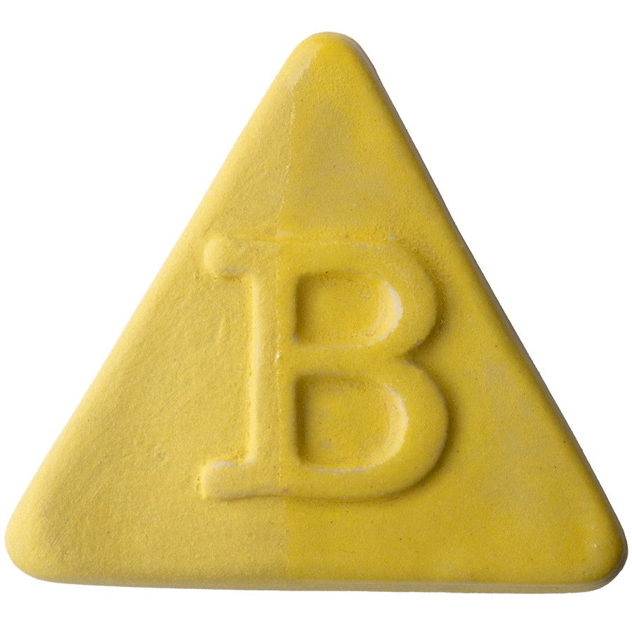 Botz Edition ist eine solide gelbe, dreieckige Tafel mit abgerundeten Kanten und einer zentralen B-Prägung, die mit transparenter Glasur für Glanz veredelt und für Brenntemperaturen von 1180–1280 °C ausgelegt ist.