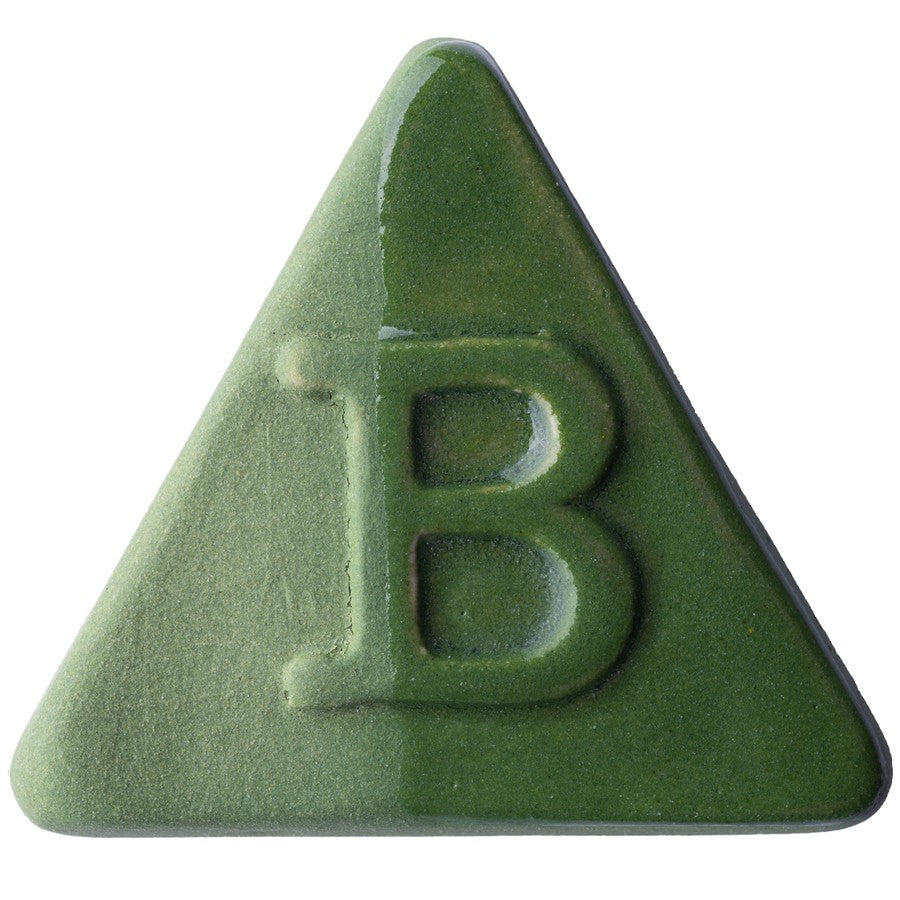 Die Botz Edition ist eine grüne, dreieckige Keramikfliese mit glänzender und matter Oberfläche, einem erhabenen Buchstaben B in der Mitte und einer transparenten Glasurbeschichtung.