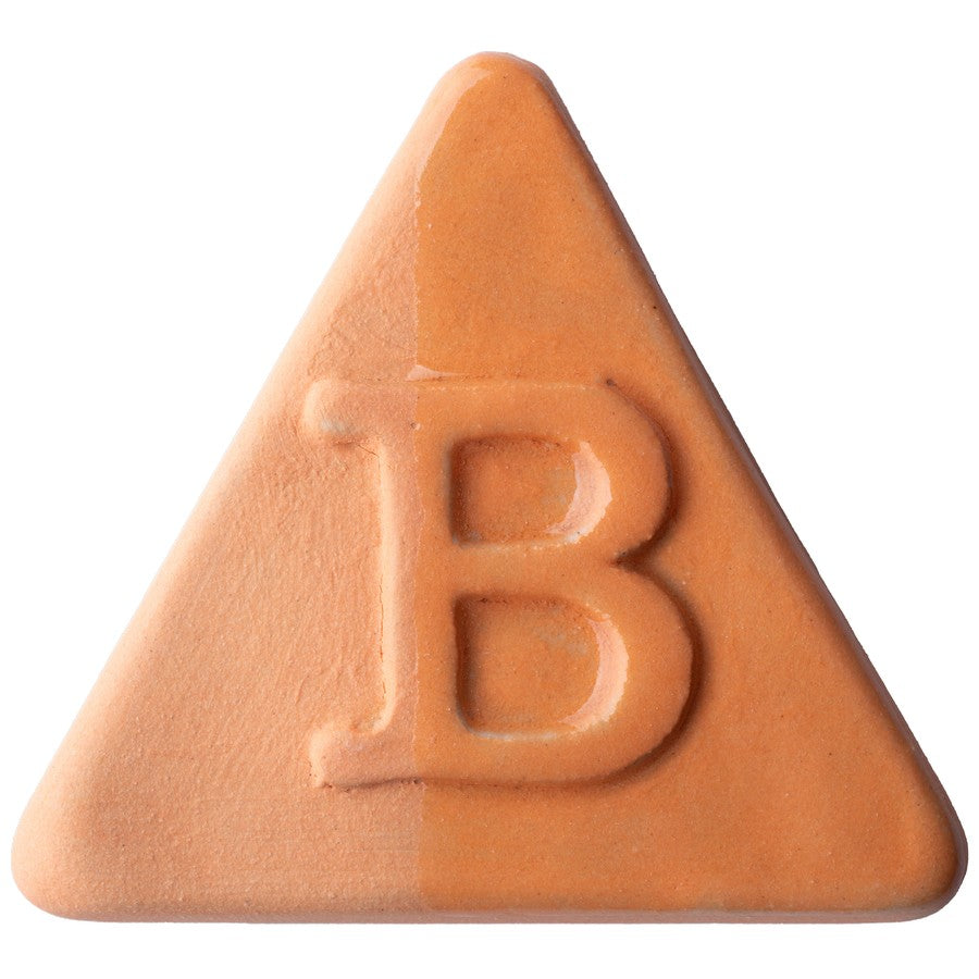 Eine dreieckige, pfirsichfarbene Pille mit einem auf einer Seite eingeprägten „B“, inspiriert von der Botz Edition, die an Steinzeug-Engoben-Keramik mit transparenter Glasur erinnert.