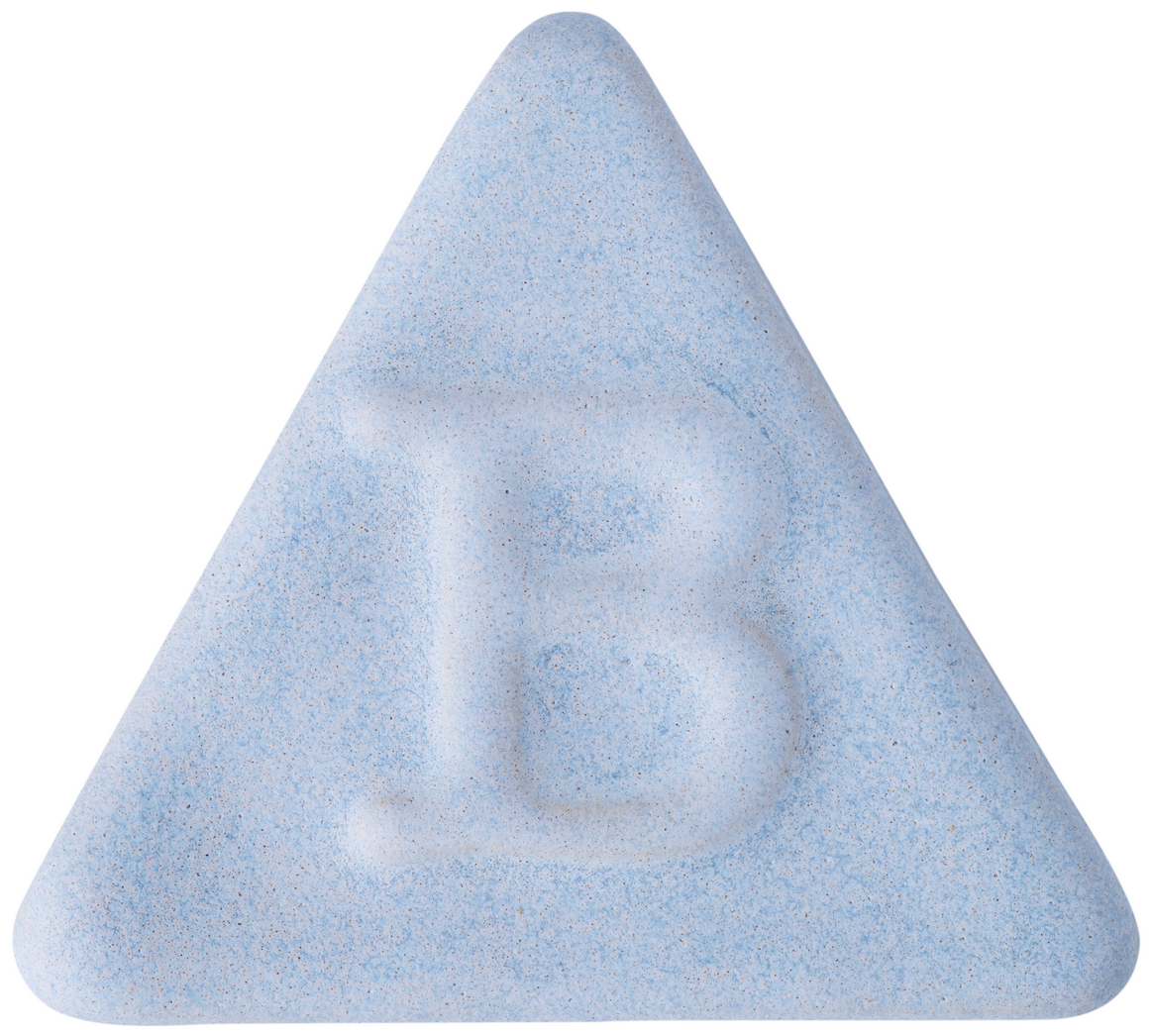 Eine hellblaue, dreieckige Tafel von Botz Steinzeug weist in der Mitte ein fett geprägtes „B“ auf, das an Oberflächen erinnert, die in einem Brennbereich bei 1220–1280 °C erzielt werden.