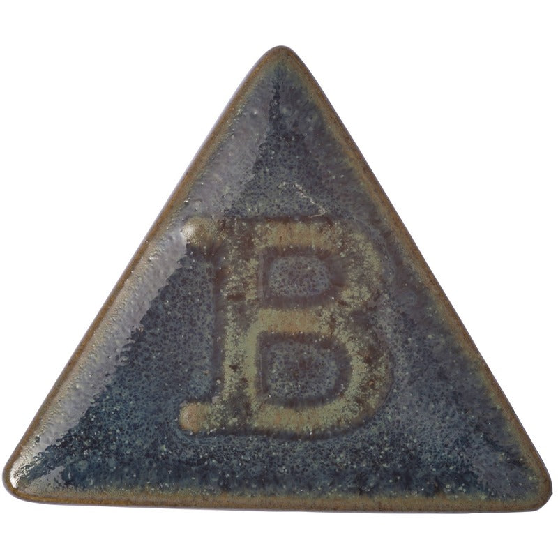 Botz Steinzeug: Ein glänzendes, dunkelblaugrünes Keramikdreieck mit einem erhabenen Buchstaben B in der Mitte. Bei 1220–1280 °C mit Steinzeugglasur gebrannt, zeugen seine leicht abgerundeten Kanten und die strukturierte, reflektierende Oberfläche von hochwertiger Handwerkskunst.