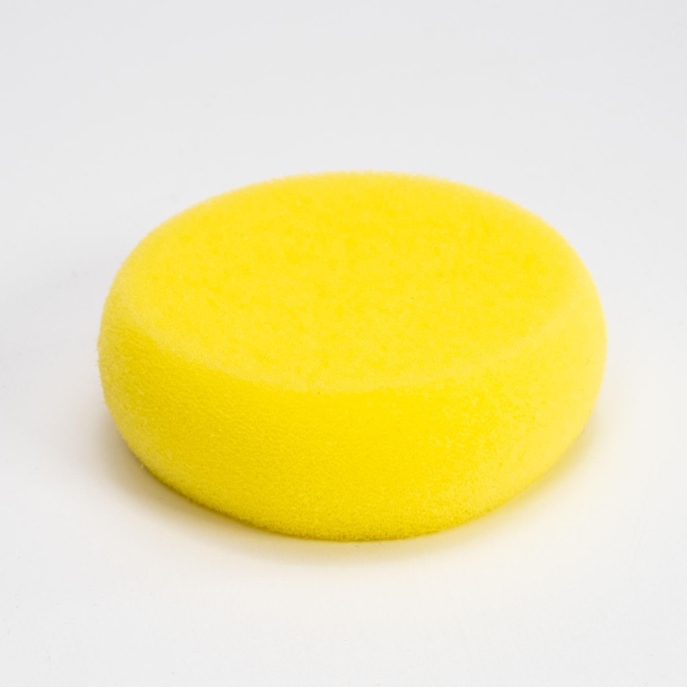 Der Schwamm Rund, ein runder Schwamm mit leuchtend gelber Farbe und weicher, strukturierter Oberfläche, liegt auf einem schlichten weißen Hintergrund.