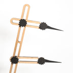 Eine Nahaufnahme des Stechmaßes - Höhenmaßes, eines geometrischen Werkzeugs mit verstellbaren Armen aus Holz und schwarzem Kunststoff und spitzen Enden, diagonal angeordnet auf einem schlichten weißen Hintergrund.
