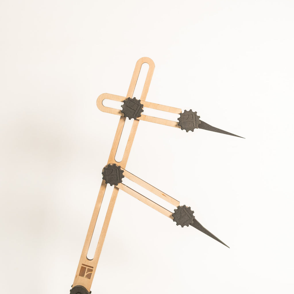 Eine Nahaufnahme des Stechmaßes - Höhenmaßes, eines Proportionaltrenners aus Holz und Metall mit verstellbaren Armen und spitzen Enden, vor einem schlichten weißen Hintergrund.