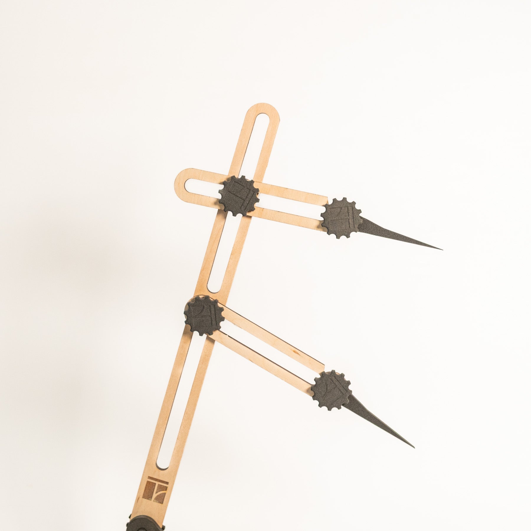 Eine Nahaufnahme des Stechmaßes - Höhenmaßes, eines Proportionaltrenners aus Holz und Metall mit verstellbaren Armen und spitzen Enden, vor einem schlichten weißen Hintergrund.