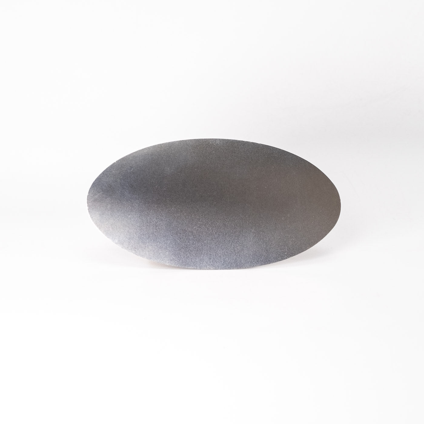 Die Ziehklinge Oval, ein flacher, ovaler Schaber aus Edelstahl mit glatter, matter Oberfläche, ist auf einem schlichten weißen Hintergrund angebracht.